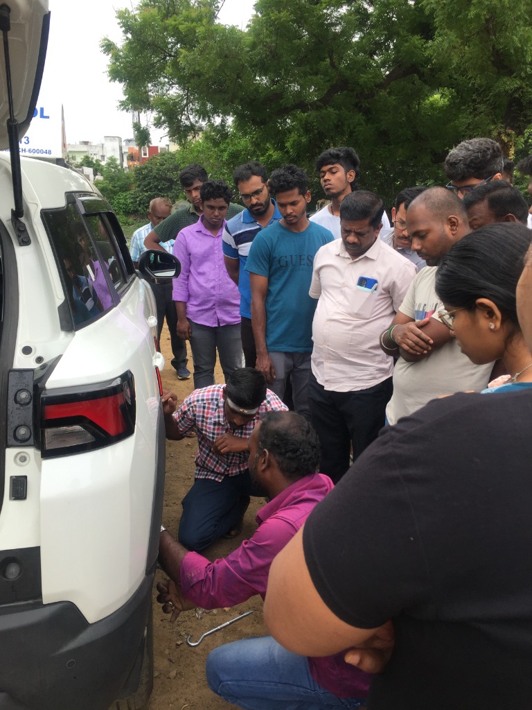 JK Driving School instructor demonstrating tyre replacement and mechanical maintenance to students